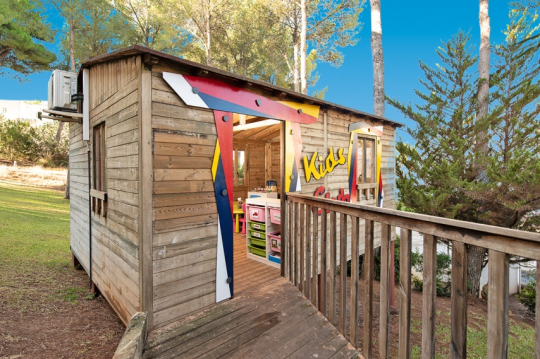 Holzhütte mit offener Tür und der Aufschrift Kids Club